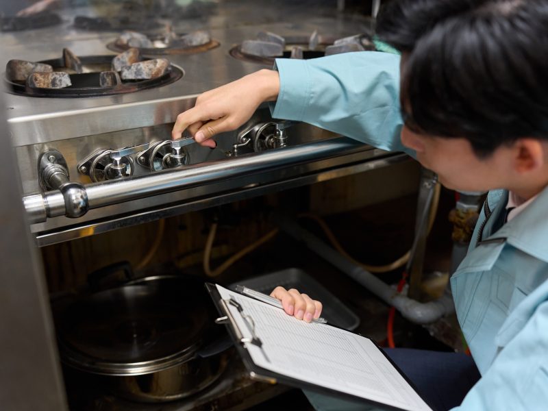 A man checking a gas stove at a restaurant